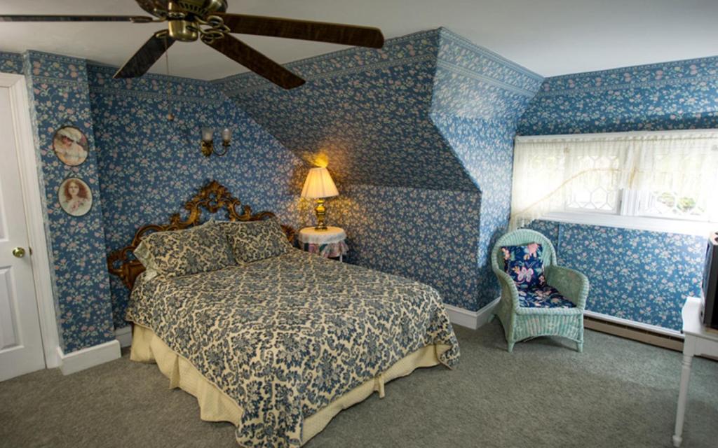 a bedroom with blue walls and a bed and a fan at Thornhedge Inn in Bar Harbor