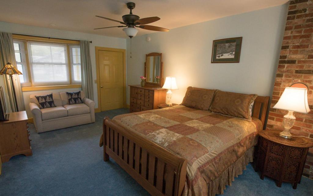 a bedroom with a large bed and a couch at Thornhedge Inn in Bar Harbor