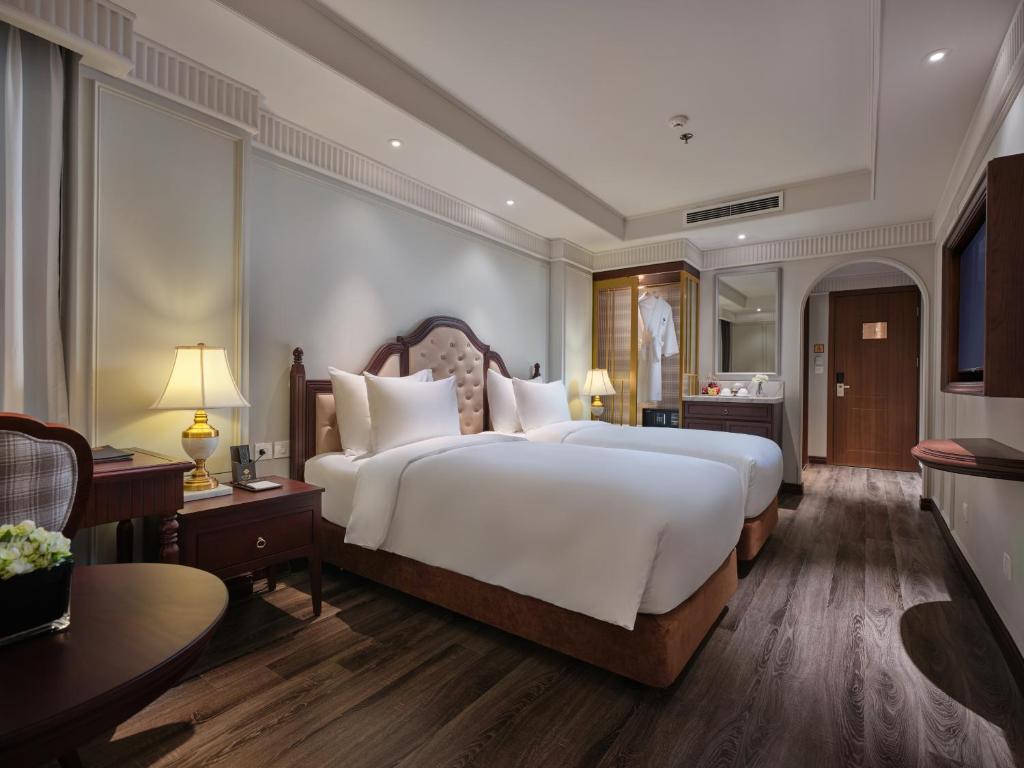 a bedroom with a large white bed and a desk at GRAND HOTEL du LAC Hanoi in Hanoi