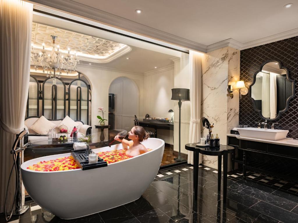 a woman in a bath tub in a bathroom at GRAND HOTEL du LAC Hanoi in Hanoi
