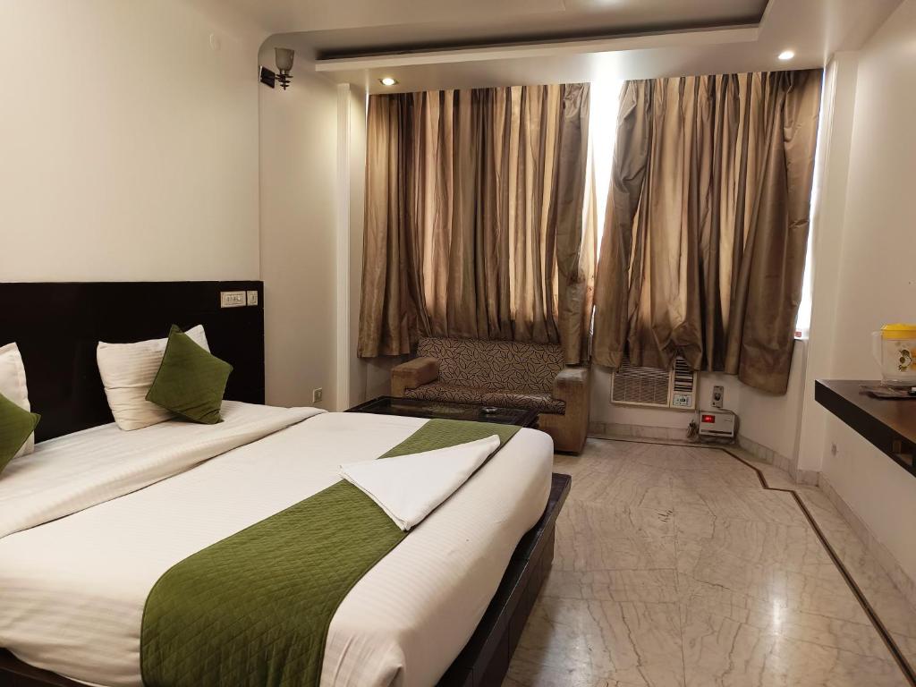 a bedroom with a large bed and a window at Hotel Tarrk Near IGI Airport in New Delhi