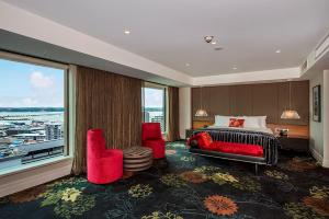 a bedroom with a bed and two chairs and a large window at The Grand by SkyCity in Auckland +37 photos