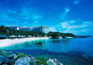 a beach with chairs and umbrellas in the water at Shangri-La Mactan, Cebu in Mactan