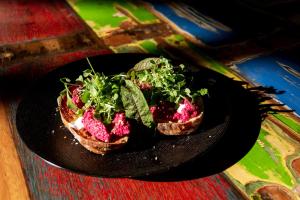 dois pedaços de pão com verduras num prato preto em Majango Bungalows em Kuta Lombok