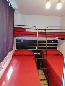 una camera con 2 letti a castello con lenzuola rosse di Camping Delfino ad Albenga