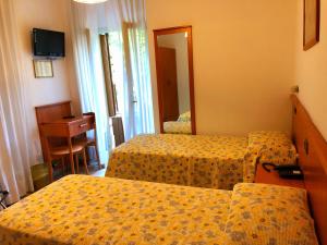 una camera d'albergo con due letti e uno specchio di Hotel Sanmicheli a Verona Altre 37 foto