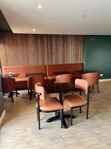 a waiting room with chairs and a table and a table and chairs at Kozi Suites Nairobi Airport in Nairobi +37 photos