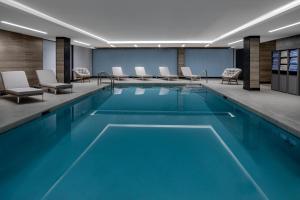 a pool in a hotel room with blue water and chairs at Four Points by Sheraton Flushing in Queens