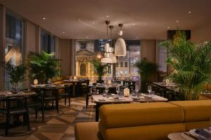 a restaurant with tables and chairs and a yellow couch at Pan Pacific London in London