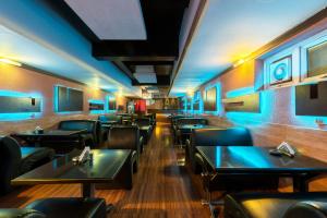 a restaurant with black tables and chairs and blue lights at Treebo ESS Grande in Coimbatore