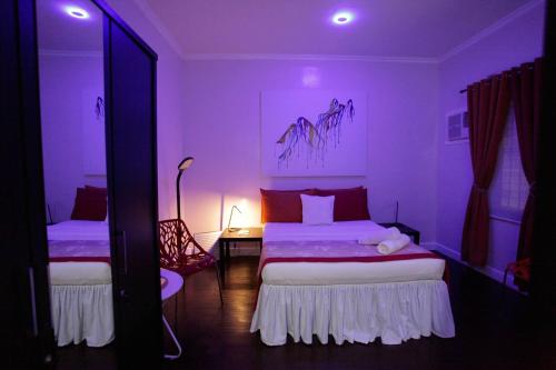 a bedroom with two beds with purple lighting at HalfWay House Hostel Mactan Cebu Airport in Mactan