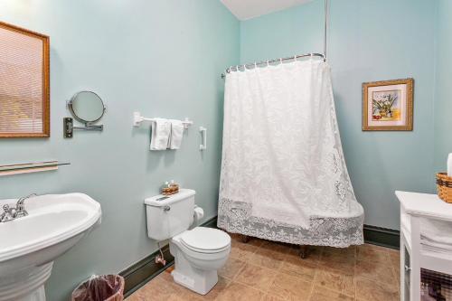 a bathroom with a white shower curtain and a toilet at Spencer House Inn in Saint Marys