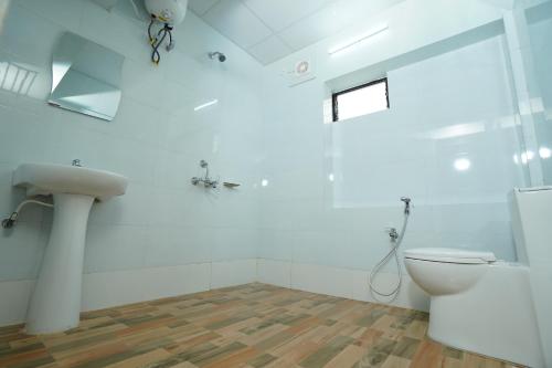 a white bathroom with a toilet and a sink at Hotel Royal Palace in Guwahati
