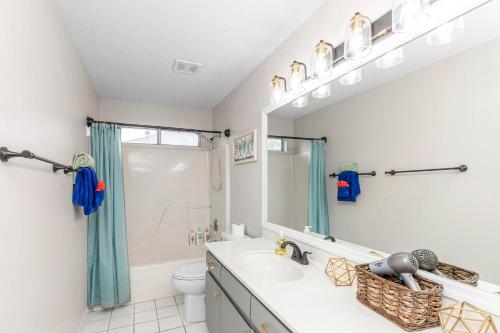 a bathroom with a sink and a toilet and a mirror at Breeze - Family Retreat with Waterfront Access & Game Room in Navarre