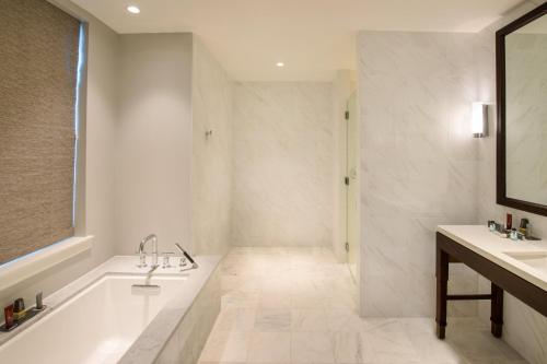 a white bathroom with a tub and a sink at Marriott Syracuse Downtown in Syracuse