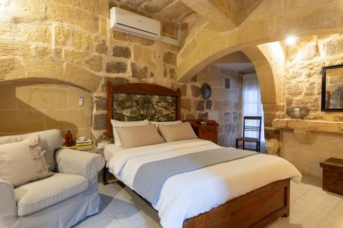 a bedroom with a large bed and a chair at Gozobreak Farmhouses in Kerċem